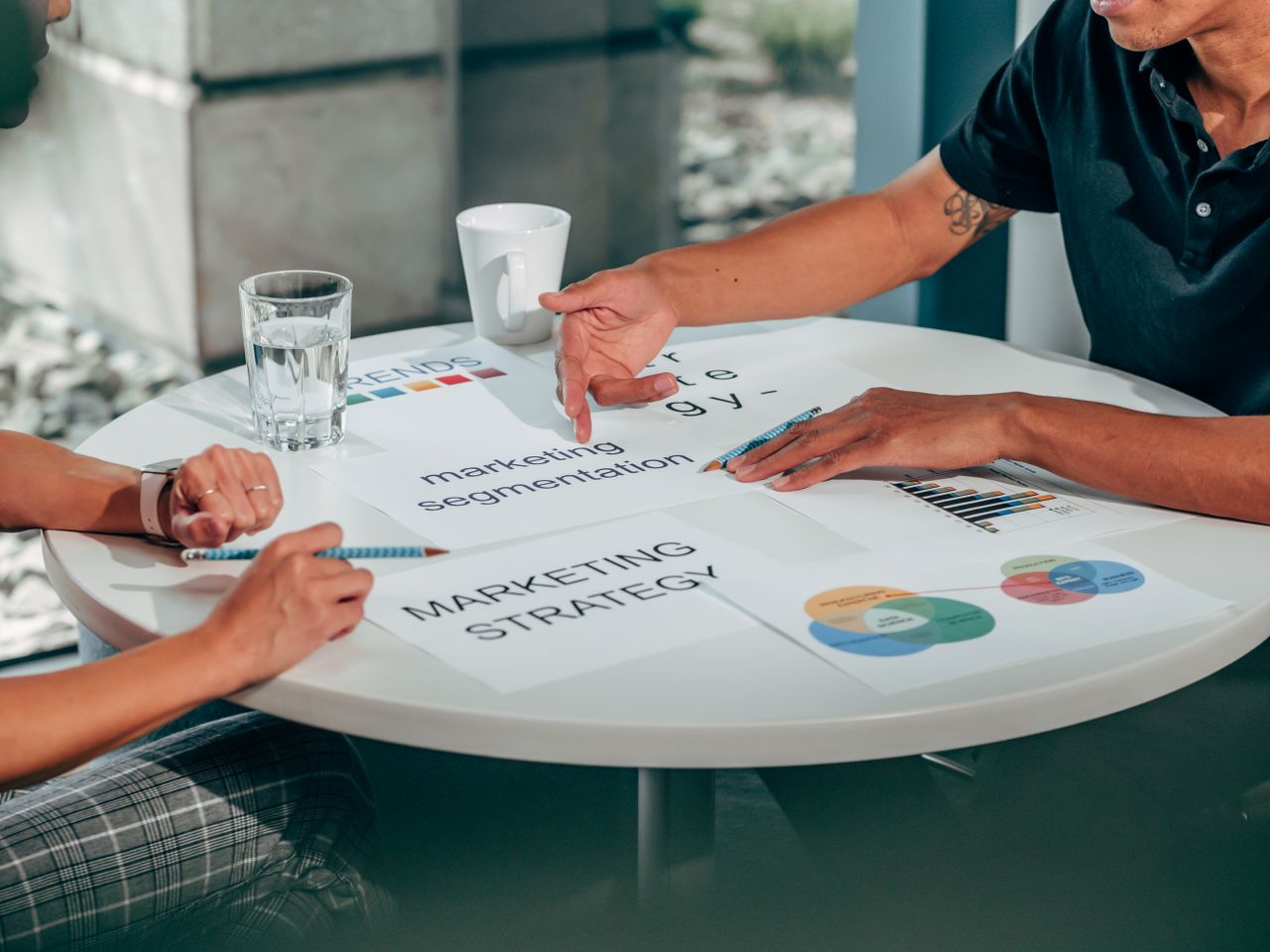 about-02 Two adults in an office talking through a marketing strategy around a round table.